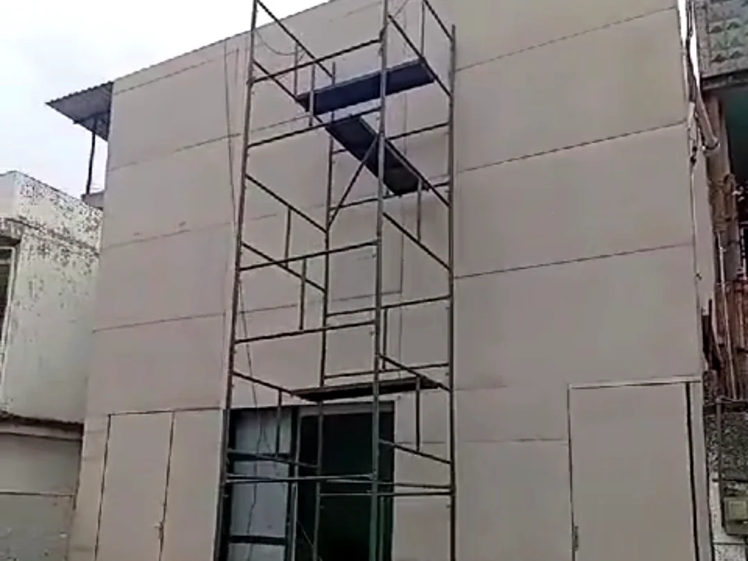 Fachada com placas cimentícias já instaladas sobre a estrutura metálica e portão de acesso concluído